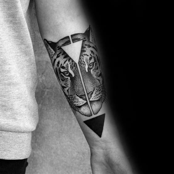 Forearm tattoo of a realistic tiger face divided by a vertical line with contrasting black and white triangles for a bold geometric contrast.