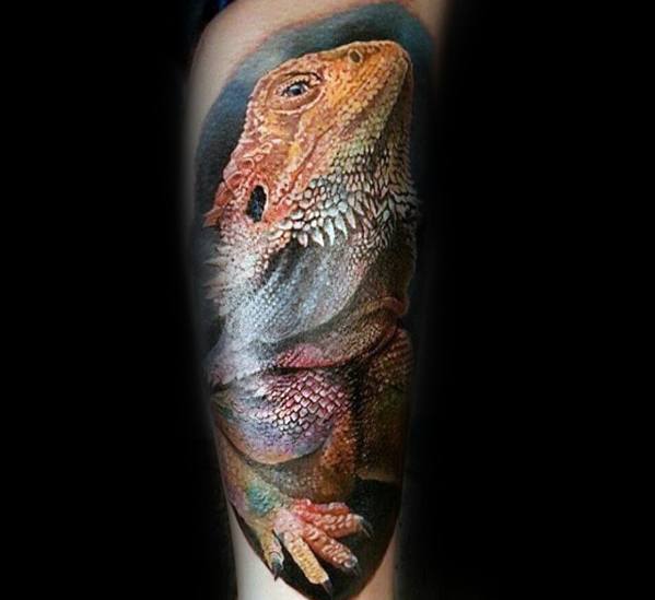 Ultra-realistic bearded dragon tattoo with detailed texture, soft lighting, and natural earthy tones wrapping around the forearm.