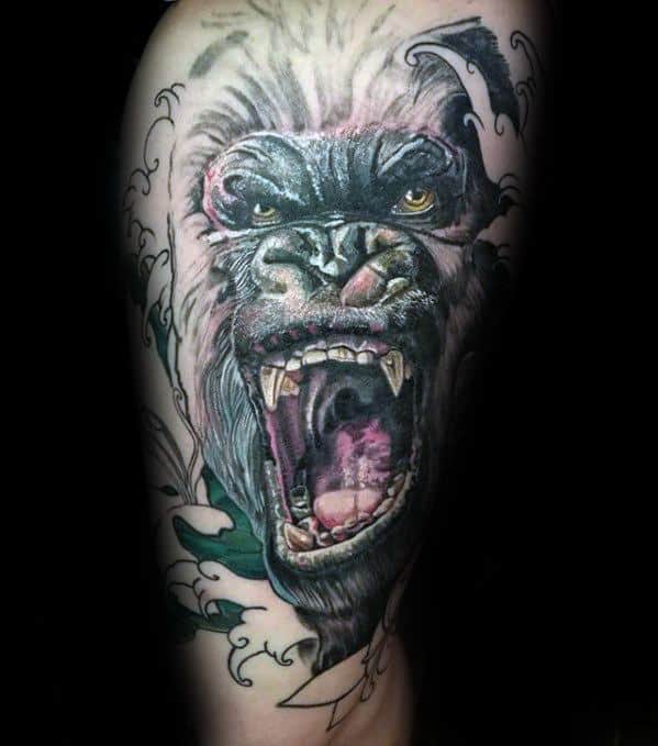 Realistic King Kong tattoo on upper arm with vivid colors, showing Kong roaring fiercely, surrounded by stylized waves and flowing lines.