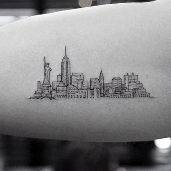 Thin line forearm tattoo of the New York City skyline featuring the Statue of Liberty, Empire State Building, and detailed cityscape.