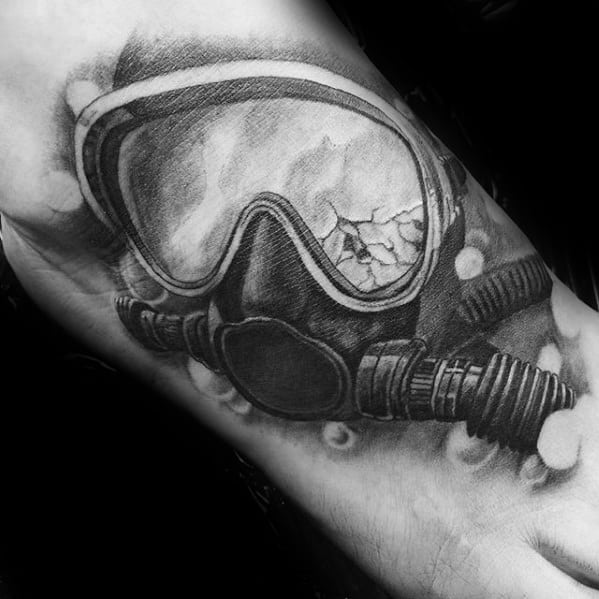 Realistic black and grey tattoo of a scuba diving mask with a cracked lens and detailed breathing hoses, surrounded by bubbles.
