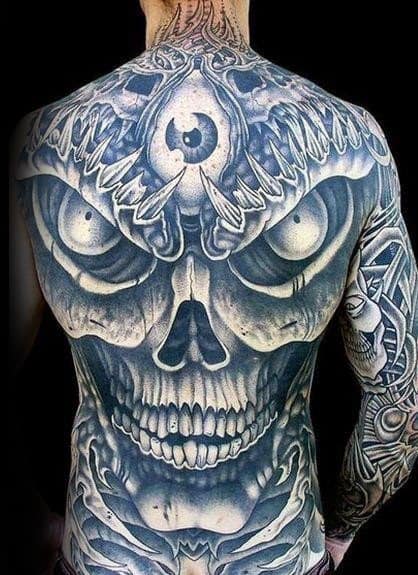 Intense full-back tattoo of a demonic skull with bulging eyes and a third eye, blending surreal detail with dark fantasy elements.
