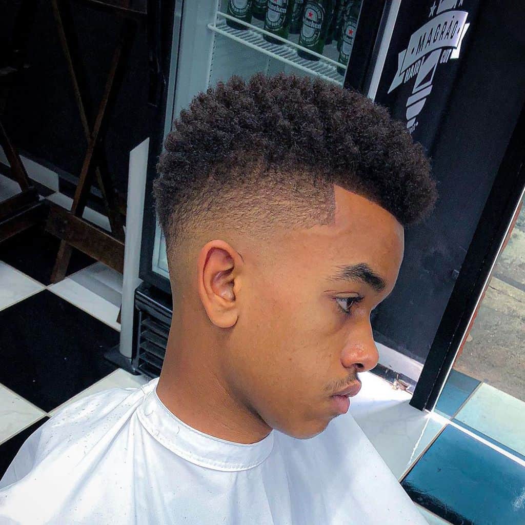 A curly hairstyle with long and texturized hair on top paired with faded sides