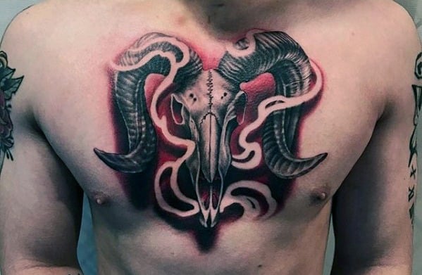 Chest tattoo of a ram skull with large horns and abstract black and red shading