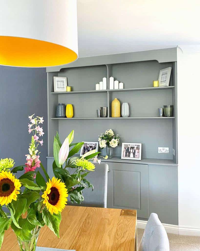 large gray cabinet with shelves wood table and chairs sunflowers framed photos vases 