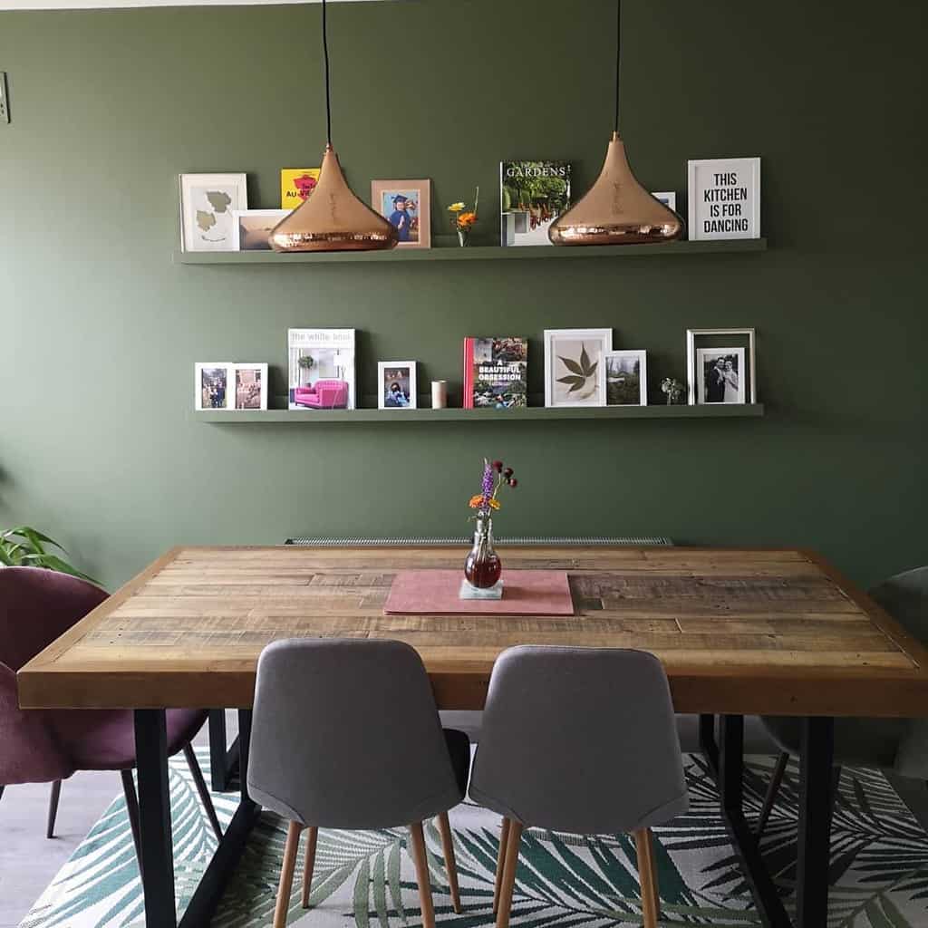 green accent wall shelves with books photos decorations wood table and chairs 