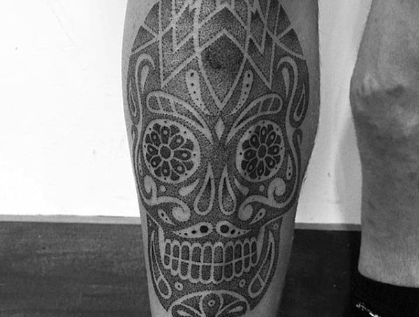 Calf tattoo for men featuring a detailed sugar skull design with dotwork and geometric patterns.