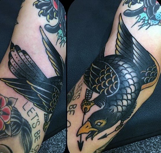 Shiny Black Raven Tattoo With Arrow on an Arm