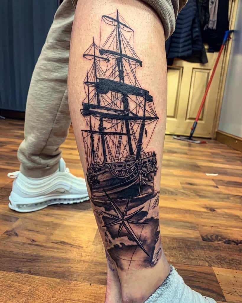 Leg sleeve tattoo of a detailed sailing ship, with a compass design beneath with map