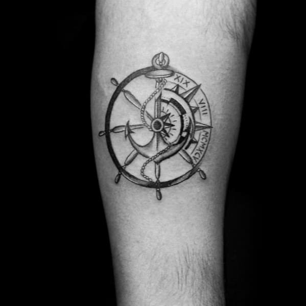 Black and gray ship wheel and anchor tattoo with intricate shading, rope details, and Roman numerals, symbolizing guidance, stability, and nautical heritage.