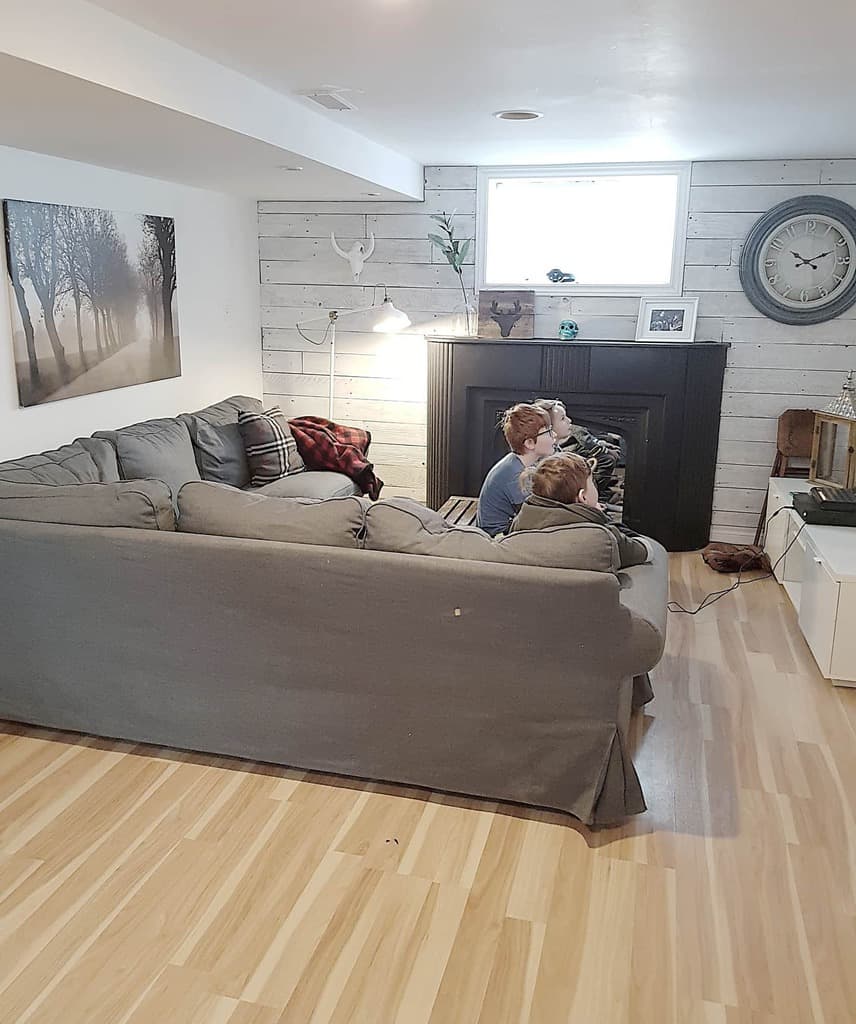Kids playing video games in cozy living room with grey sectional and shiplap walls.