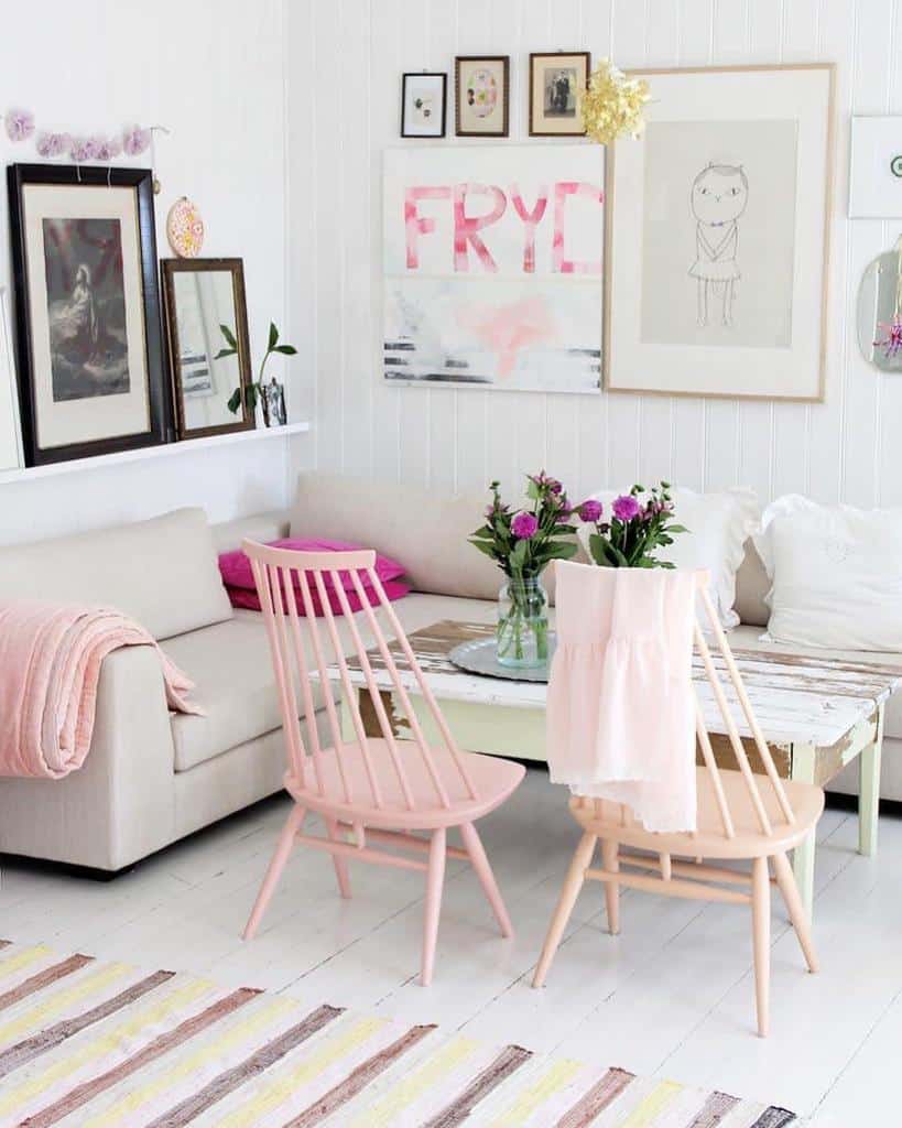 Bright living room with pink chairs, white sofa, and eclectic wall art.