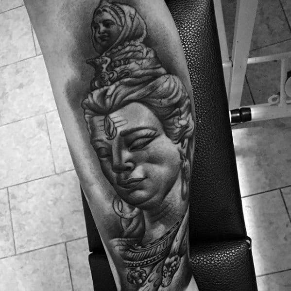 Forearm tattoo of Lord Shiva with a peaceful, downward gaze, detailed jewelry, and flowing hair topped with Goddess Ganga, blending realism and devotion.