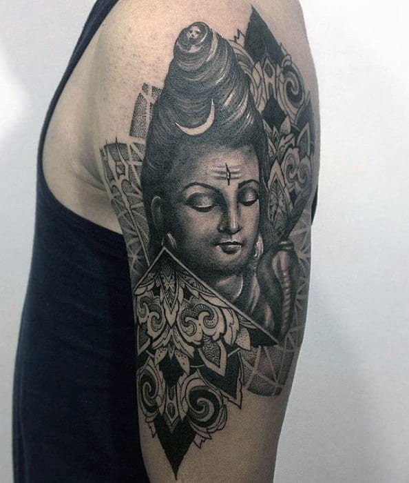 Upper arm tattoo of Lord Shiva with a calm expression, framed by intricate mandala and geometric patterns, blending sacred art with modern detail.
