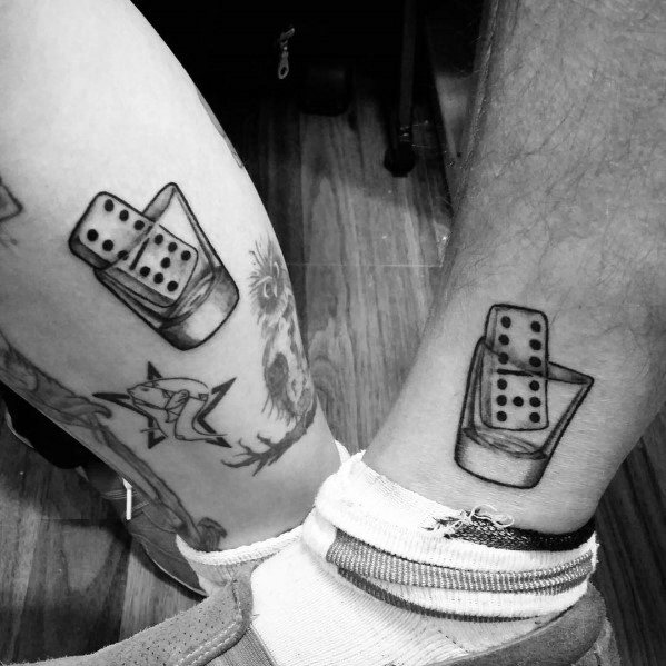 Matching black and grey shot glass tattoos featuring a domino inside, symbolizing luck and chance in a bold, minimalist design.