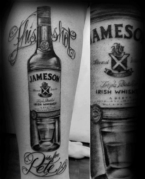 Realistic black and grey tattoo of a Jameson whiskey bottle with a shot glass, detailed script, and shading for a bold tribute design.