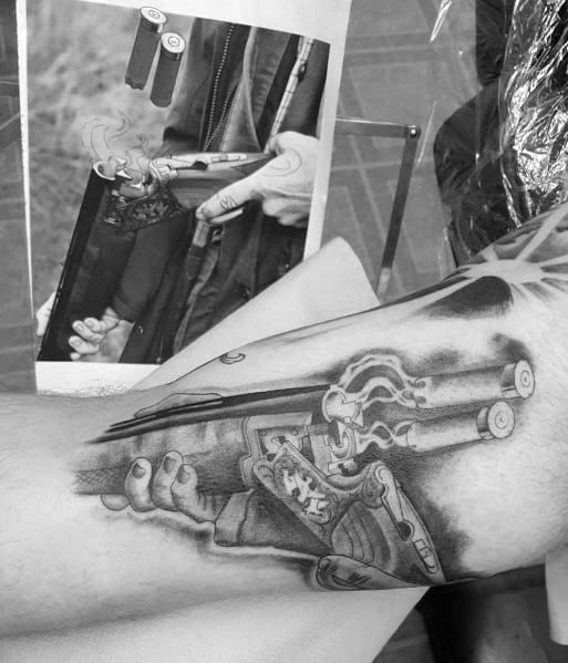 Realistic black and grey tattoo of a double-barrel shotgun being loaded, featuring intricate shading and fine details for a lifelike design.