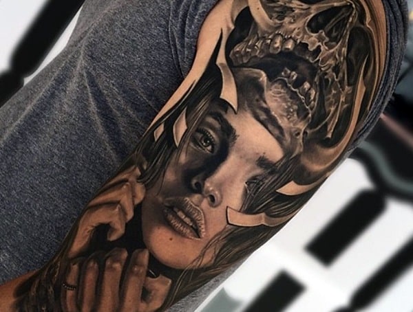 A detailed tattoo of a face blending into a skull on a person's arm