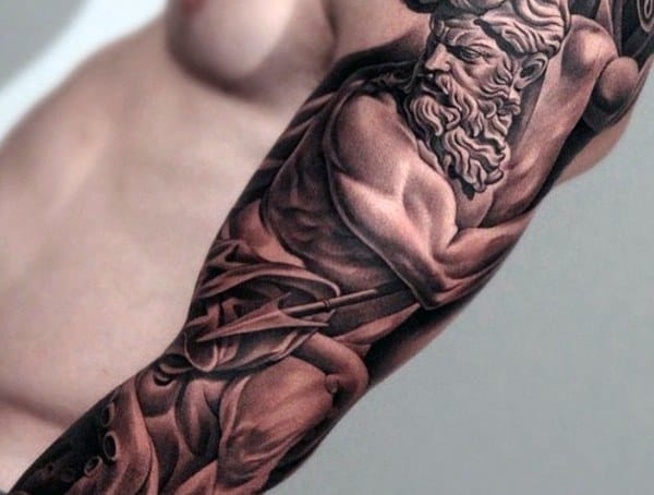 Close-up of a muscular arm tattooed with a detailed image of a bearded figure with a serious expression