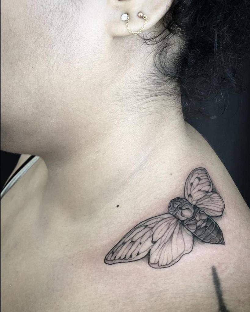 Black and white cicada tattoo on woman's neck and shoulder