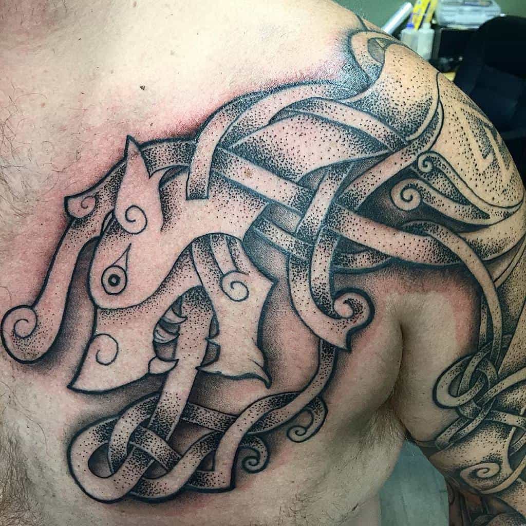 This intricate shoulder tattoo showcases a Norse wolf in knotwork, with detailed dotwork shading adding texture and depth, emphasizing strength and unity