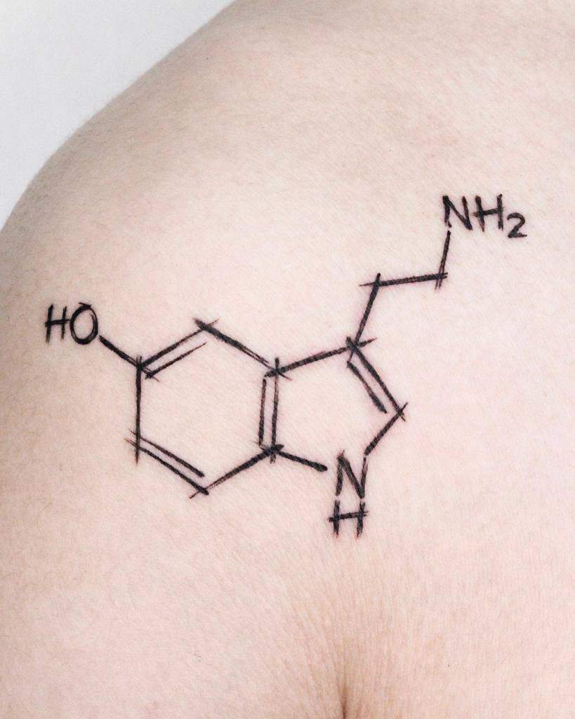 A sleek tattoo of the serotonin molecule graces the person's skin, capturing the essence of happiness and balance in its intricate design