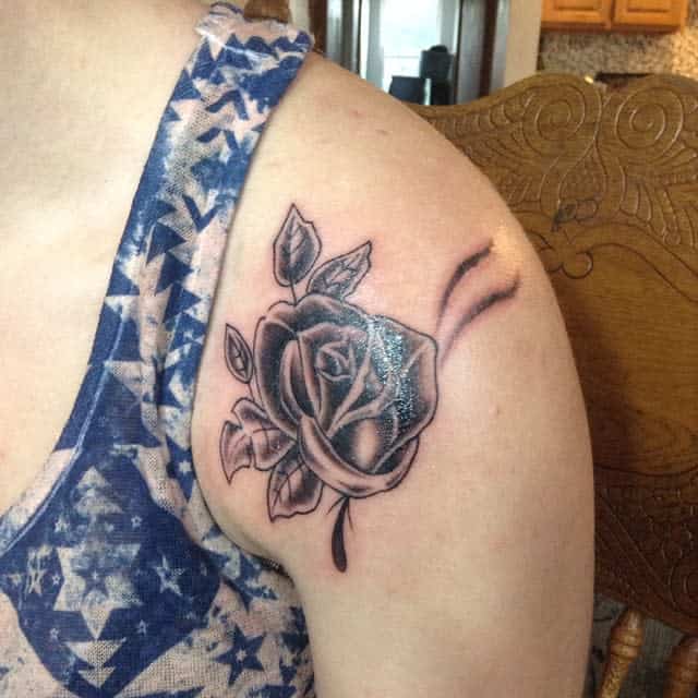 A striking black and white rose tattoo elegantly adorns the person's upper arm, capturing attention with its bold and mysterious allure