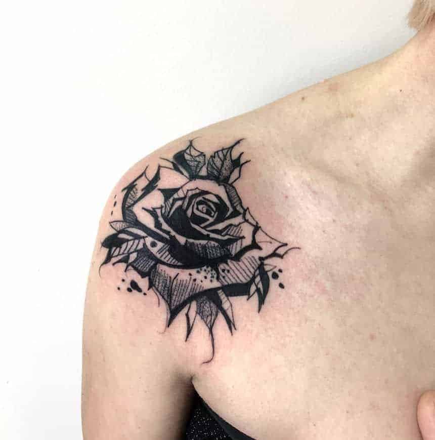 A black and gray rose tattoo on an upper shoulder