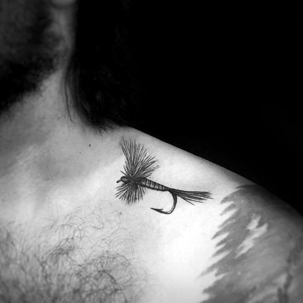 Minimalist black tattoo of a detailed fishing fly on the collarbone, symbolizing a love for fly fishing and the outdoors.