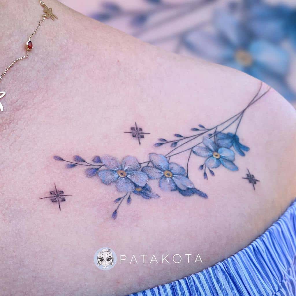 Forget me not blue flower tattoo, adorned with shimmering stars, graces the shoulder