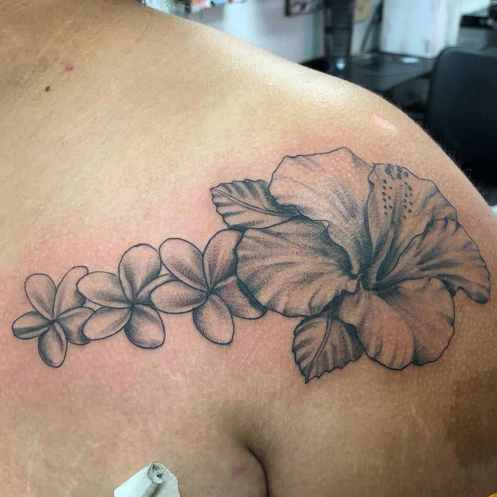 Shoulder tattoo featuring a large hibiscus flower and smaller plumeria flowers