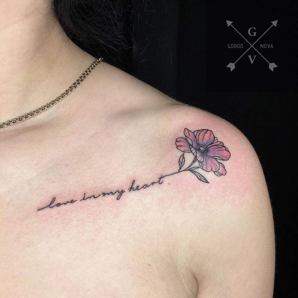 Tattoo of a pink jasmine flower and "love in my heart" text on a shoulder