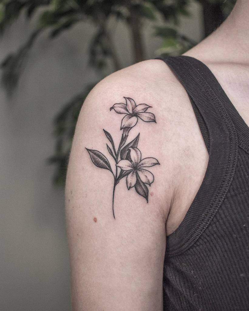 Tattoo of two jasmine flowers with leaves on the upper arm 