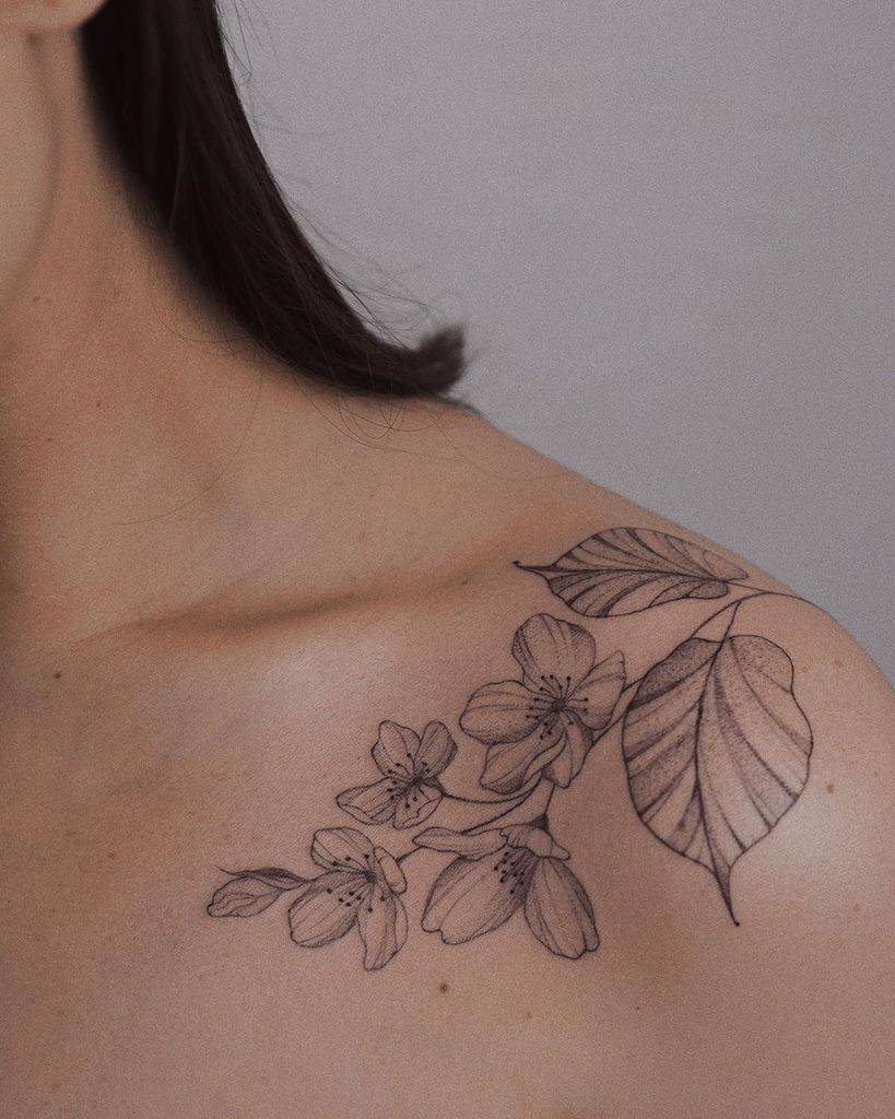Tattoo of blooming jasmine flowers and leaves on a shoulder