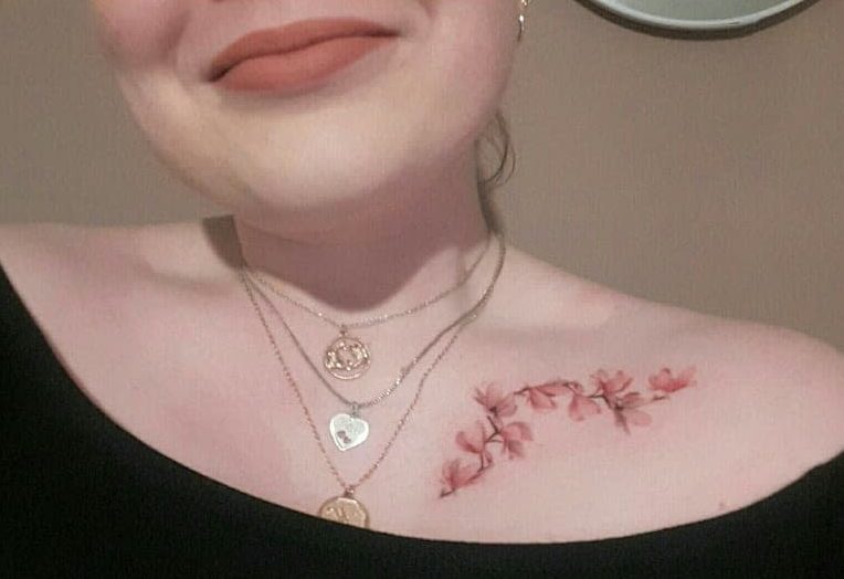 A woman displays a beautiful magnolia tattoo below her collarbone