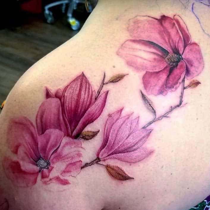 Tattoo of pink magnolia flowers with leaves beautifully adorning a person's shoulder