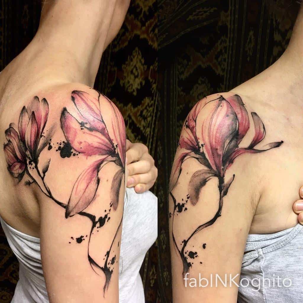 A watercolor floral tattoo graces the shoulder and upper arm, showcasing pink magnolias and delicate leaves