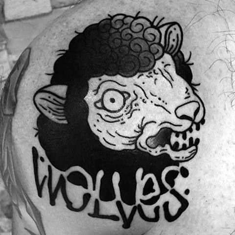 A black and white tattoo featuring a wolf with a sheep's head, with the word "Wolves" lettered below