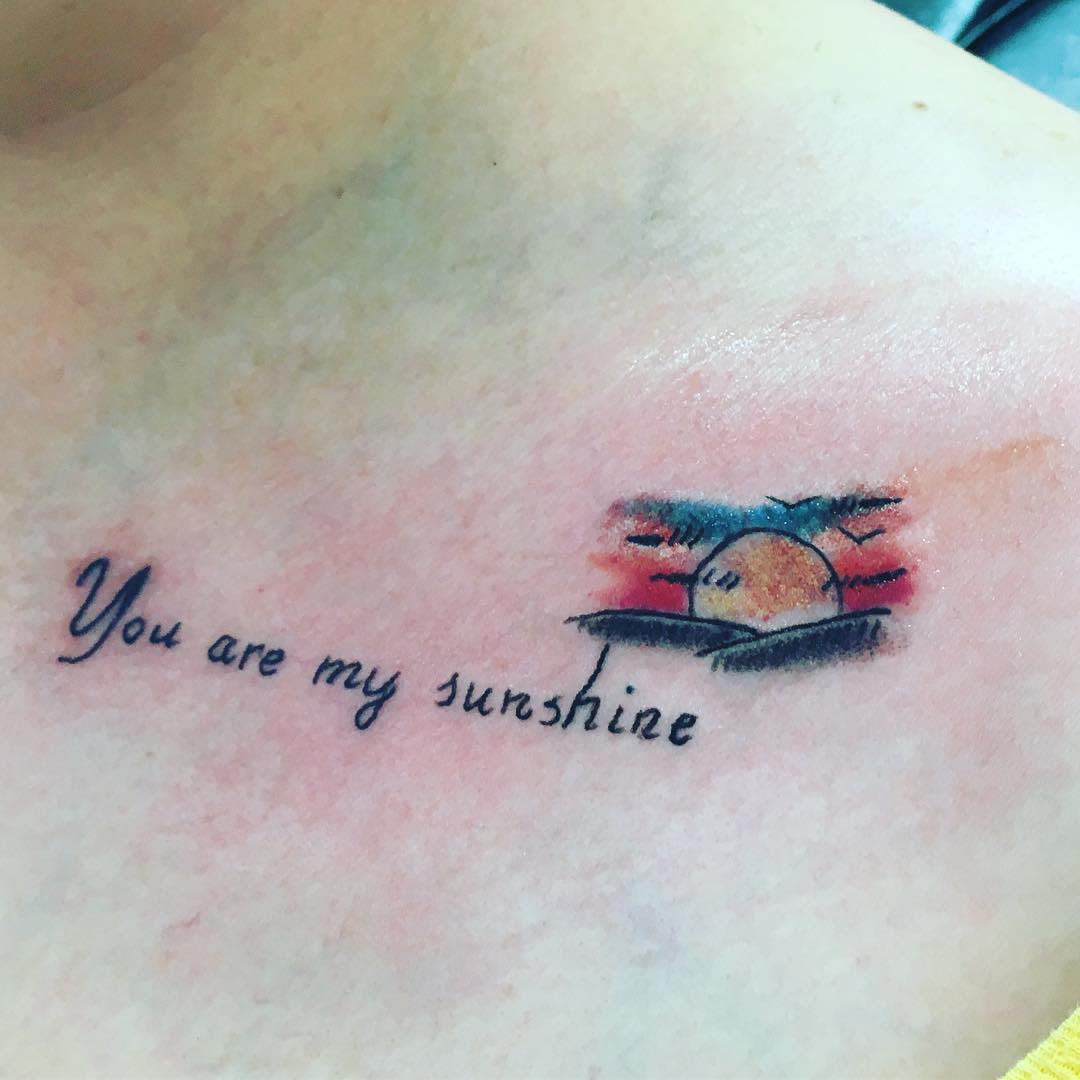 You are my sunshine tattoo with a colorful sunset design on skin