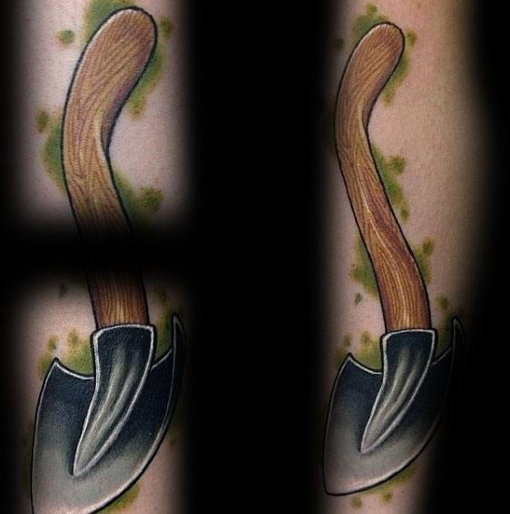 Tattoo of a bent-handled shovel with a wooden texture and shaded metal blade, surrounded by green splashes for a bold, rugged design.