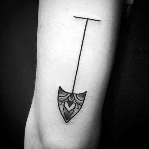 Minimalist shovel tattoo with a thin handle and a decorative, ornamental blade, blending simplicity with artistic detail for a unique design.