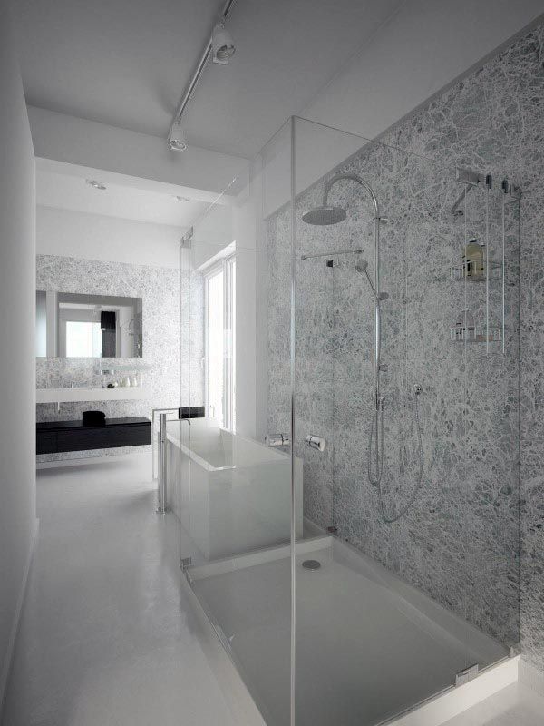Minimalist bathroom with glass shower enclosure, marble walls, and freestanding bathtub.