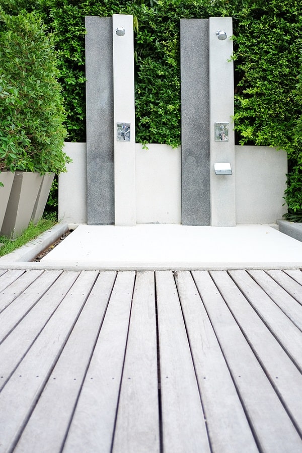 Twin modern outdoor showers with sleek panels and wooden decking.