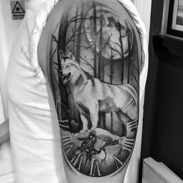Black and gray Siberian Husky tattoo on a man's upper arm, featuring a forest scene, full moon, and broken clock for a mystical, timeless design.
