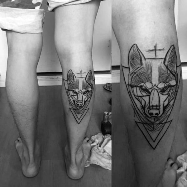 Geometric Siberian Husky tattoo on a man's calf, featuring fine line work, overlapping triangles, and a minimalist cross for a modern aesthetic.