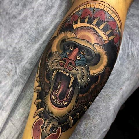 Neo-traditional baboon tattoo with bold colors, intricate details, and tribal elements, featuring a fierce open-mouthed expression for a powerful design.