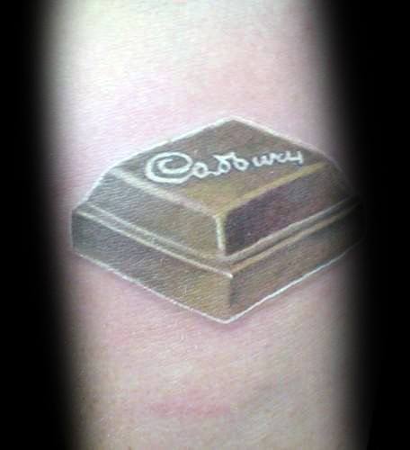 Realistic tattoo of a single Cadbury chocolate piece with detailed shading and highlights, creating a 3D effect on the skin.