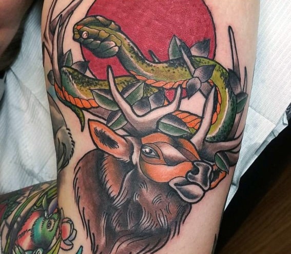 Vibrant neo-traditional elk tattoo featuring bold colors, a coiled snake, and a red sun backdrop for a striking and dynamic design.