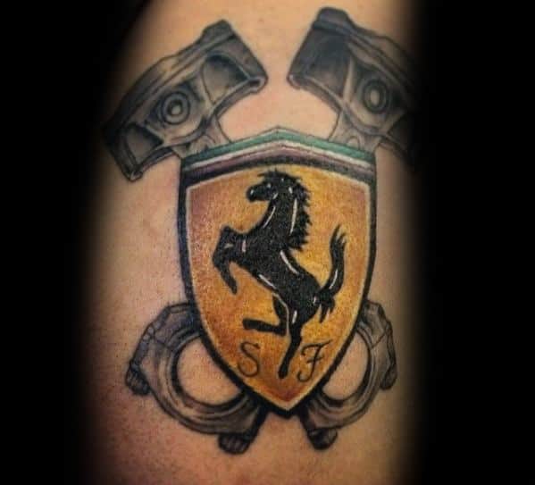Ferrari shield tattoo with crossed engine pistons in background, symbolizing racing heritage, power, and mechanical precision, inked on man's arm.