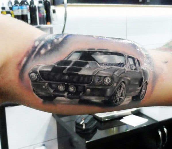 Realistic Ford Mustang tattoo on bicep, featuring a bold black muscle car with racing stripes, intricate shading, and a dynamic perspective.